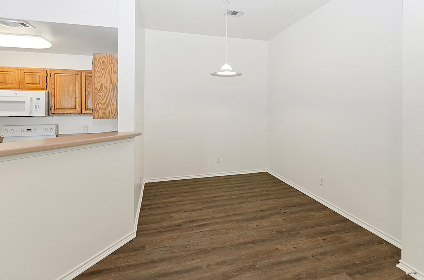 An empty dining room with hardwood floors at the Cypress View Villas Apartments in Weatherford, Texas.